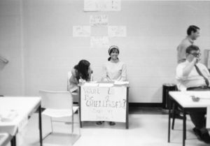 "Want to Be a Cheerleader?" sign at a sign-up table for Suffolk University's cheerleading squad, circa 1960