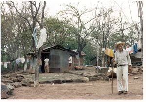 Unidentified man standing in front of a house in an unidentified rural village in El Salvador, 1986