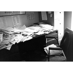 A desk covered with piles of papers.