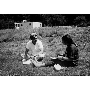 Carlos Luna (left) and Clara Garcia (right) sitting in a field during a staff outing.