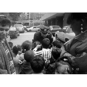 Policeman talks to a crowd of children who are gathered to attend Joseph Kennedy's visit to Villa Victoria.