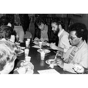 Men and women sharing a meal at a table during a community gathering.