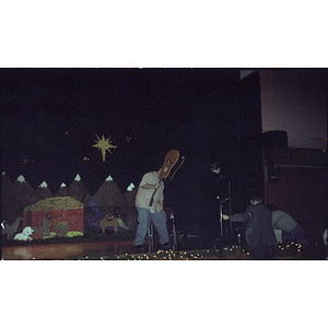 Man takes a seat on stage with his guitar during a Three Kings Day celebration.