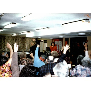 People raising their hands to speak at a community meeting.