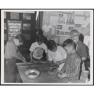 Four boys working on projects for their pottery class as an instructor stands behind them at the Boys' Clubs of Boston