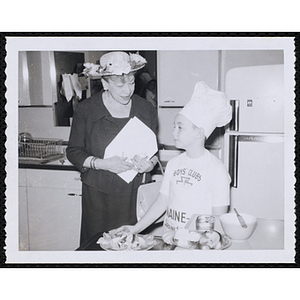 A member of the Tom Pappas Chefs' Club poses with an unidentified woman in a kitchen