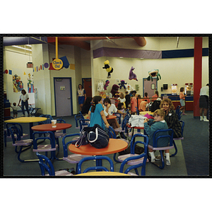 Children and adults sit at tables in a Chuck E. Cheese's