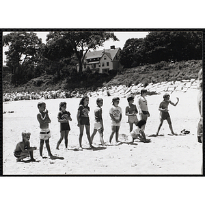 A group of children line up to play a game on a beach