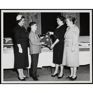 Boy is presented with the American flag from unidentified woman at Marters Club event