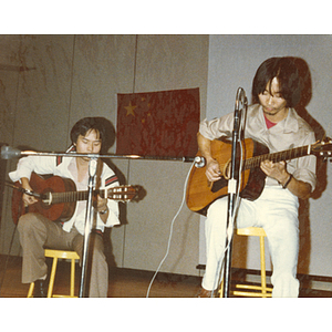 Two Chinese men play guitar onstage in the Josiah Quincy School auditorium at the 30th anniversary celebration of the People's Republic of China