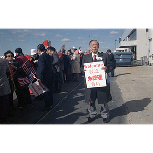 Member of the Chinese Progressive Association holds a poster for an event at Boston Logan Airport to welcome Zhu Rongji, Premier of the People's Republic of China