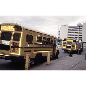Two Boston Public School buses parked along a sidewalk in Boston