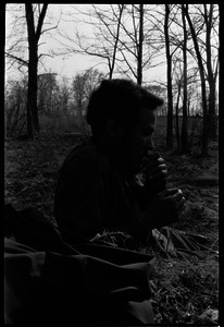 Man seated in the woods near McGuirk Stadium