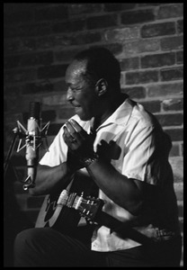 Josh White performing on guitar in a coffeehouse