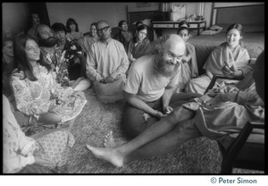 Ram Dass and others seated on the floor at the feet of Swami Muktananda