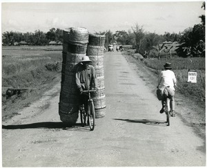Man on bicycle hauling stacks of baskets