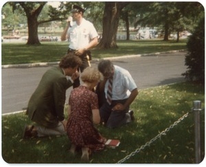 Group of two men and a woman kneeling in prayer at the peace vigil in front of the White House