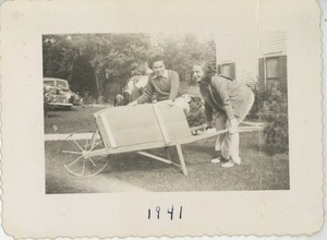 Bernice Kahn pushing wheelbarrow with unidentified friend inside