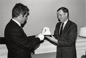 Mayor Raymond L. Flynn being presented with statue by unidentified man with cast on right hand