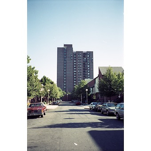 Street in the Villa Victoria neighborhood, with an apartment building high rise at the end of the street.