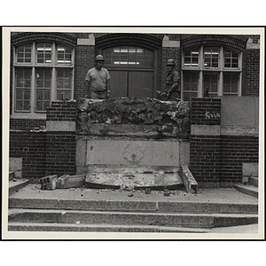 Two workers pose while removing the memorial stone outside the Charlestown Boys' Club at 15 Green Street during the renovation