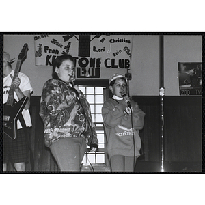 Two girls singing into microphones during the Boys and Girls Clubs of Boston 100th Anniversary Celebration event at the Charlestown Boys & Girls Clubhouse