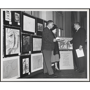 "Judges Joseph L.C. Santoro, Mrs. Gertrude M. Tonsberg, and Arthur Parker, extolling the merits of ceramic works" in the Boys' Clubs of Boston Fine Arts Exhibit at the Bunker Hill Branch of the Boston Gas Company