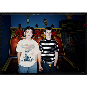 Two boys pose in front a skeeball installation in a gaming arcade