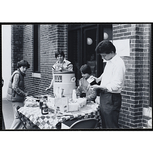 A man, teenage boy, and two girls stand around a craft table at a party