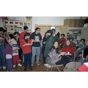 Guests hold plates of food at the Chinese Progressive Association's office during a celebration of the Chinese New Year