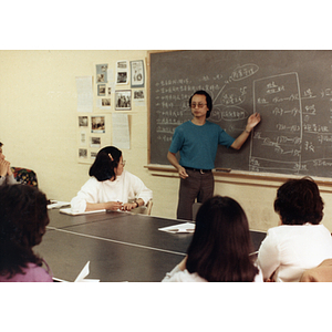 Man stands at a chalkboard while teaching at a job training class