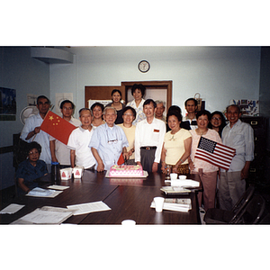 Chinese Progressive Association members gather around a man who is cutting a cake