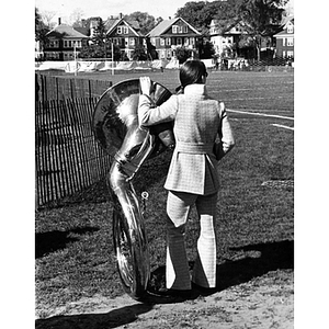 Student with a tuba on the sidelines of Parsons Field