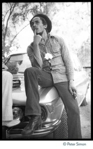 Bob Marley seated on the hood of his BMW at his house in Kingston