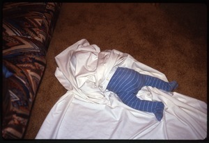 Baby lying on floor wrapped in sheet