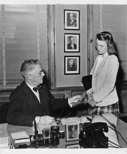 Hugh P. Baker in his office desk and speaking with student