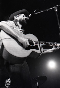 New Riders of the Purple Sage opening for the Grateful Dead at Sargent Gym, Boston University: John 'Marmaduke' Dawson playing acoustic guitar and signing with Mickey Hart in background