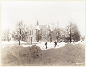 Two men shoveling snow in front of Bapst Library during winter