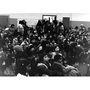 Audience, consisting mostly of Hispanic American children, seated on the floor, at a Three Kings' Day celebration at La Alianza Hispana