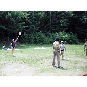 Hispanic American woman hits a volleyball, while her team watches.