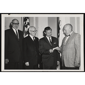 A man presenting a check to a group of men at the Kiwanis Club's Bunker Hill Postage Stamp Luncheon