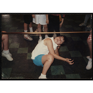 A Girl crouches under a pool cue during a limbo contest