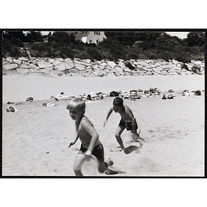 Two boys run on a beach