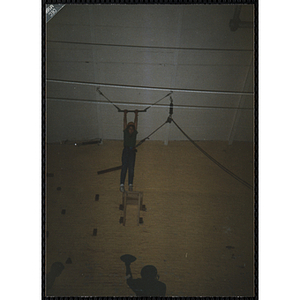 A child stands on a platform in a gymnasium