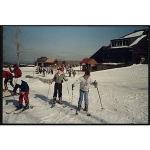 Children stand on skis near a lodge