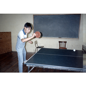 During a Chinese Progressive Association picnic, a young man plays ping pong in a recreation room