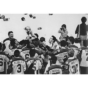 Men's ice hockey team holding up the Beanpot Tournament Trophy