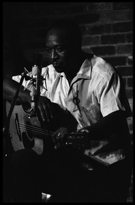 Josh White performing on guitar in a coffeehouse