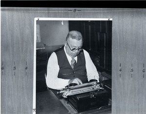 Michael Hennessey, seated at desk with Royal typewriter