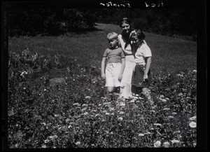 Dorothy Thompson, her son Michael Lewis, and unidentified girl standing in a field of flowers